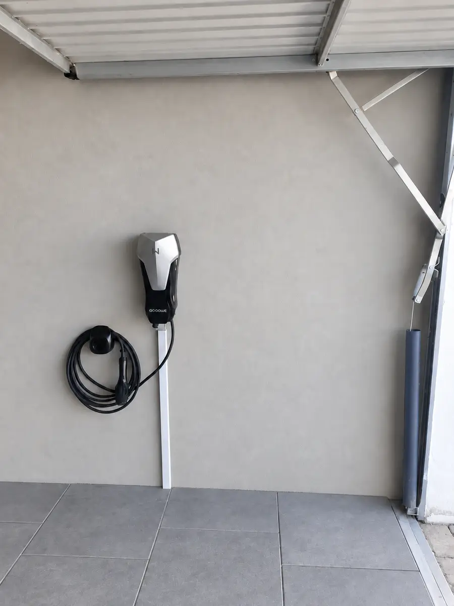 Wallbox mit ordentlich aufgehängtem Ladekabel an einem überdachten Stellplatz