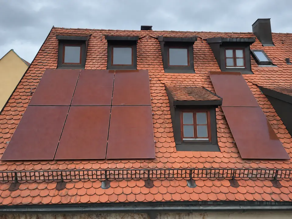 Denkmalschutzgerechte Photovoltaikanlage mit roten Modulen auf einem historischen Ziegeldach